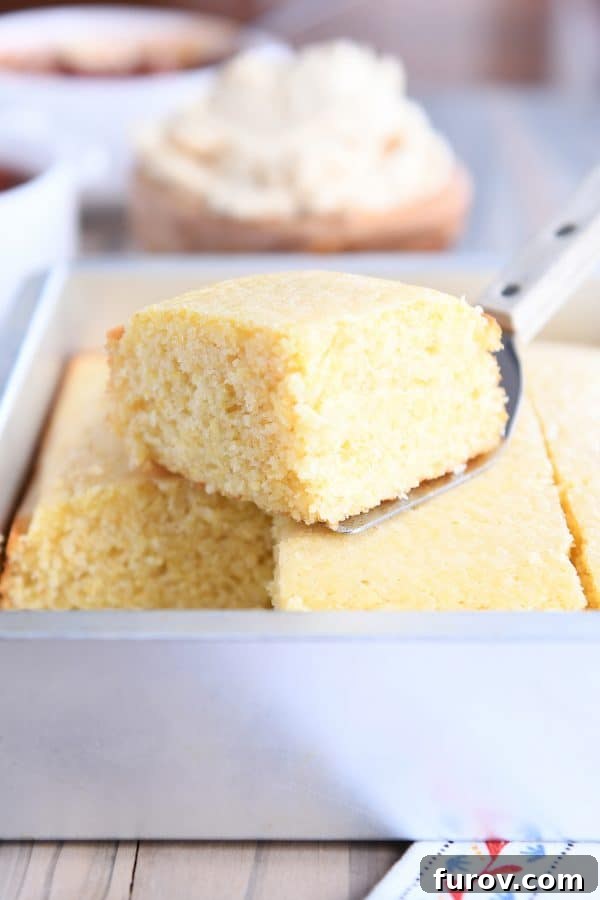 A warm, freshly cut piece of cornbread being lifted from the baking pan with a spatula, ready to be served.