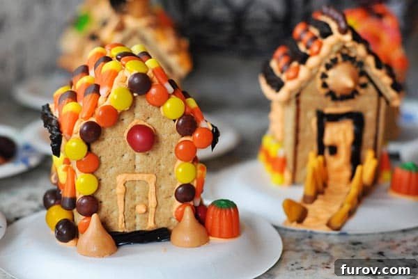 Halloween-themed decorated graham cracker houses on white plates ready for a spooky celebration