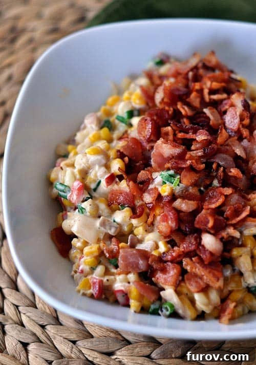 A warm, inviting bowl of creamy confetti corn and bacon, glistening with its rich sauce and ready to be served, showcasing the delicious blend of ingredients.