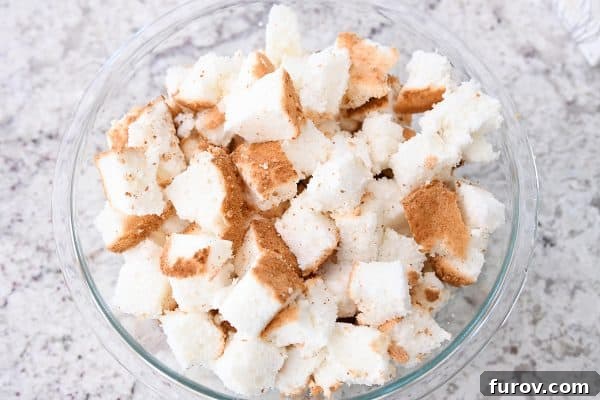 A bowl filled with uniformly cubed angel food cake pieces, perfectly prepared to form the base of the dessert.
