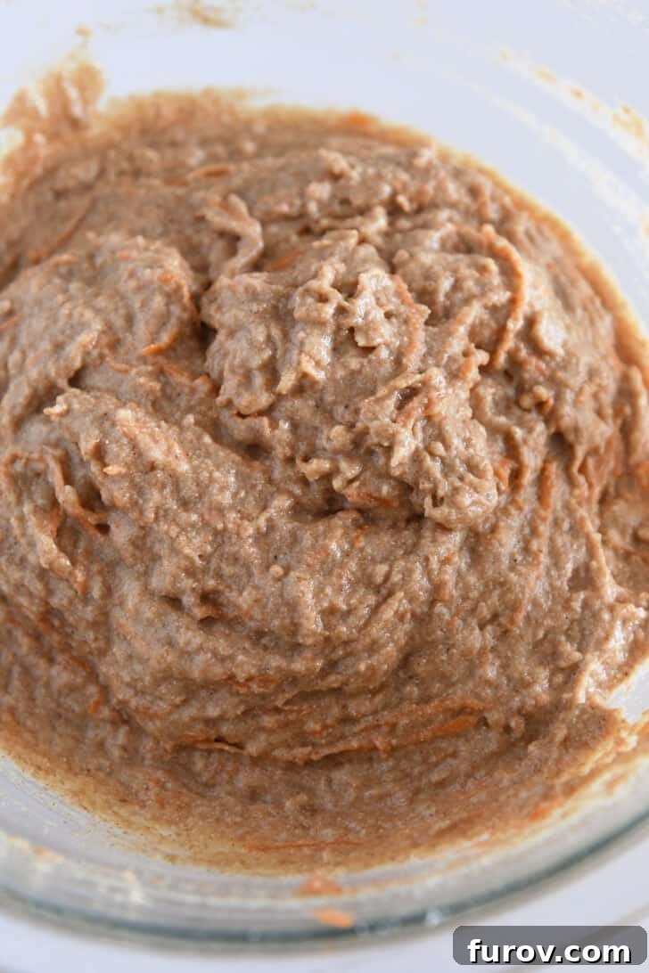 Healthy Carrot Cake Muffins with Applesauce 5 Smooth carrot cake muffin batter in a clear glass mixing bowl.