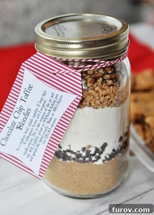 Blondie Indulgence Jar 5 A close-up of a mason jar, showcasing the carefully layered dry ingredients for the chocolate chip toffee blondie mix, tied with rustic twine and a gift tag.