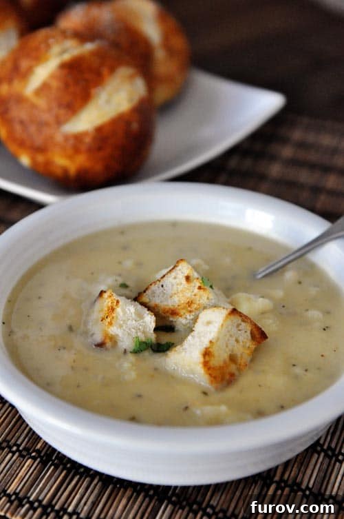 White bowl full of cauliflower soup with three big croutons on top.