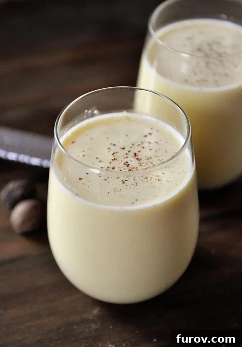 Glass full of homemade eggnog with sprinkled nutmeg on top.