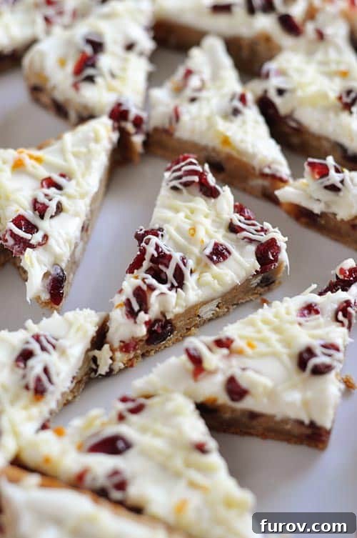 Top view of white chocolate drizzled cranberry bliss bars cut into triangle shapes, highlighting the festive toppings.