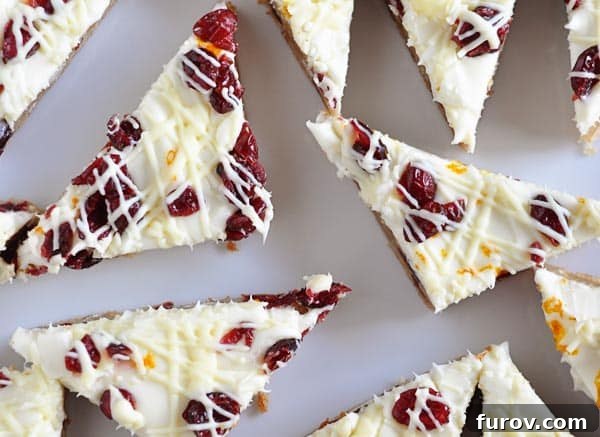 Top view of white chocolate cranberry bliss bars cut into triangle shapes on a wire rack to cool.