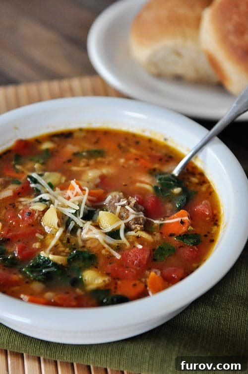Rustic Tuscan Sausage and Cannellini Bean Soup 2 A vibrant bowl of Tuscan Sausage and White Bean Soup, brimming with tender pasta, fresh spinach, and ripe tomatoes, ready to be enjoyed.