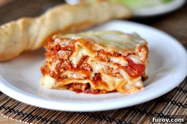 Our Beloved Holiday Rituals Captured This Weekend 8 A hearty piece of classic Italian lasagna served on a white plate alongside a golden breadstick, ready for a festive meal.