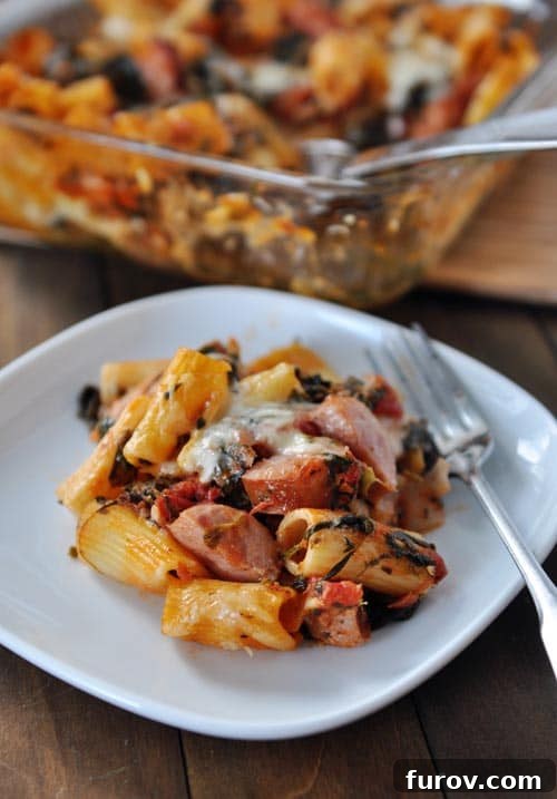Savory Chicken Sausage Pasta Bake 4 Baked pasta, cheese, chicken sausage, and a fork on a white plate.
