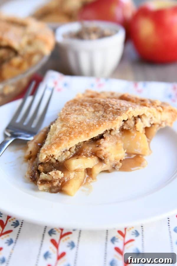Golden Toffee Crunch Caramel Apple Pie 2 A delectable slice of Toffee Crumble Caramel Apple Pie on a white plate, showcasing its rich caramel apple filling and crispy toffee topping.