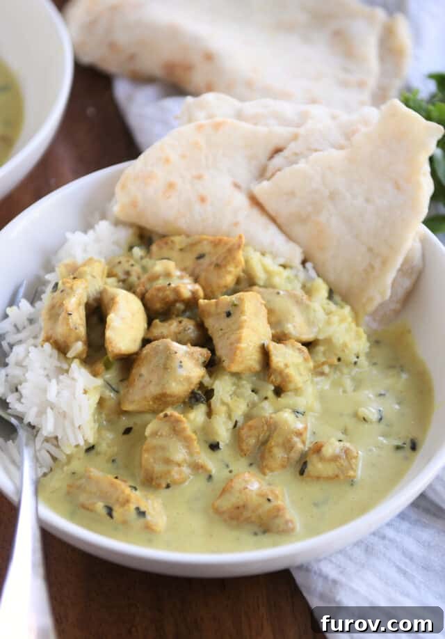 Emerald Basil Coconut Chicken 2 White bowl with rice, fork, chicken pieces, coconut curry sauce, naan. A perfect serving of Basil Chicken in Coconut Curry Sauce.
