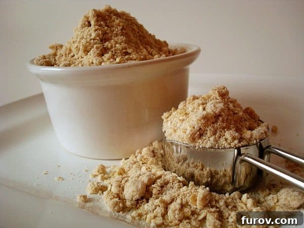 A white bowl and metal measuring cup full of homemade oatmeal pancake mix.