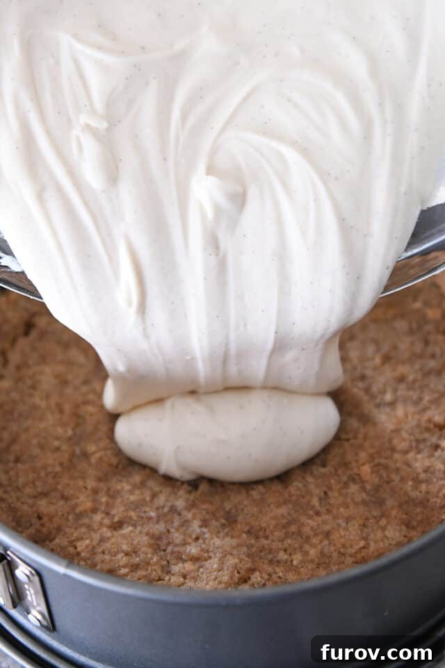 Pouring cheesecake batter onto graham cracker crust.