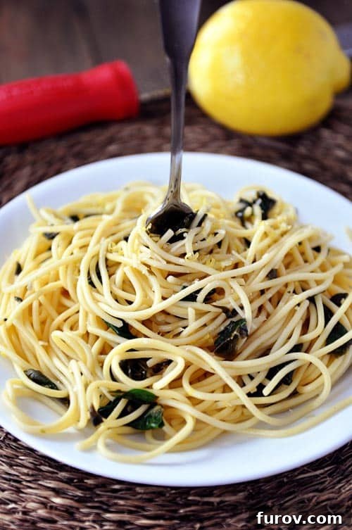 Top view of a plate full of cooked spaghetti with a fork in the middle, garnished with fresh herbs.