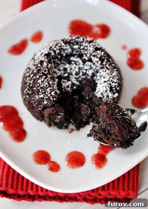 An overhead view of a single chocolate molten fudge cake on a white plate, elegantly dusted with powdered sugar, ready to be enjoyed.