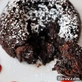 A top-down view of a small chocolate molten fudge cake on a plate, garnished with powdered sugar, ready for serving.