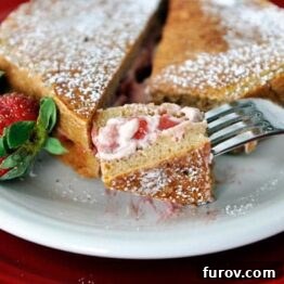 Close-up of golden brown French toast stuffed with strawberries and cream cheese, ready to serve.