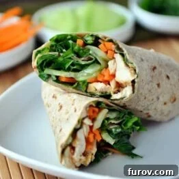 A close-up of a Thai Chicken Crunch Wrap, sliced in half to reveal the vibrant filling of chicken, vegetables, and sauce.