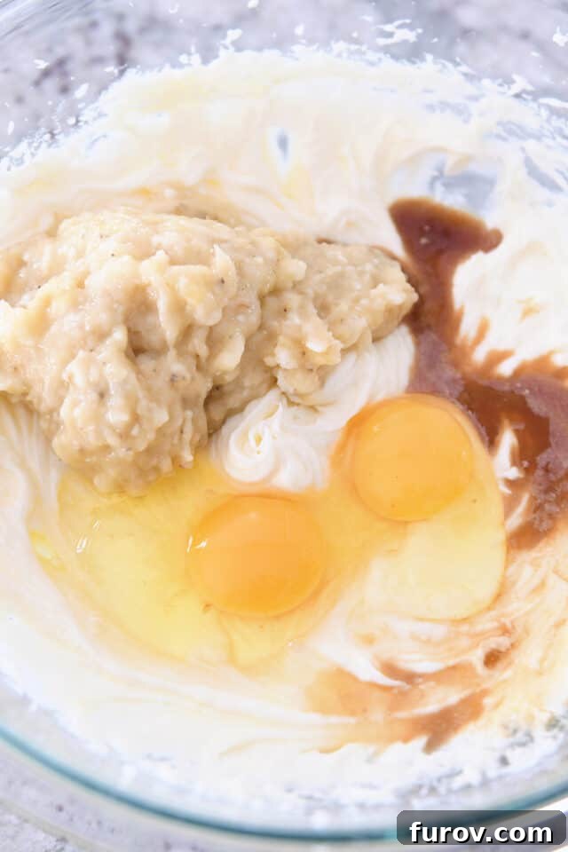 Eggs, mashed bananas, and vanilla mixed into the banana bread batter in a bowl.