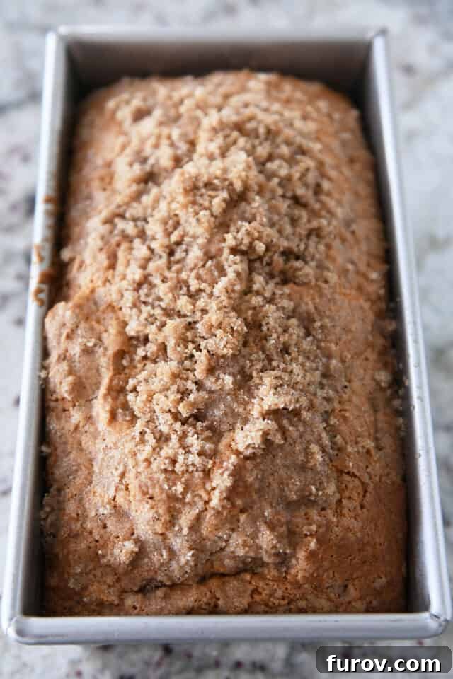 Freshly baked loaf of cream cheese banana bread in its bread pan, golden brown with a visible cinnamon topping.