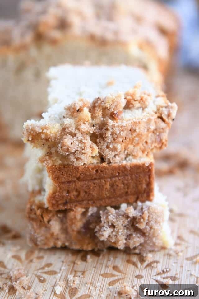 Three half slices of cream cheese banana bread stacked on a rustic wood cutting board, highlighting the moist interior.
