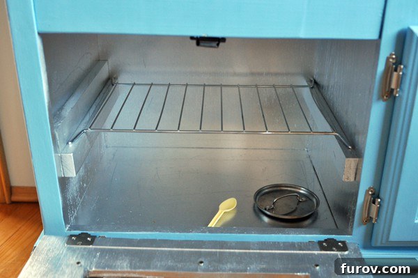 Play kitchen oven interior showing a doll and toy accessories