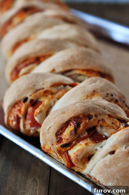 A cookie sheet full of whole wheat pepperoni pull-apart rolls, fresh from the oven and golden brown.