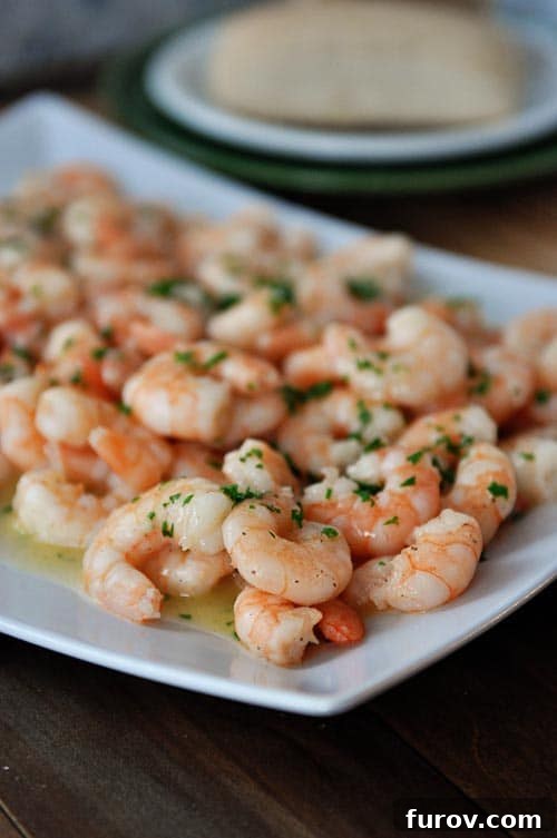 Family Favorite 20-Minute Shrimp Scampi 2 A white platter full of perfectly cooked shrimp scampi, glistening with garlic butter sauce.