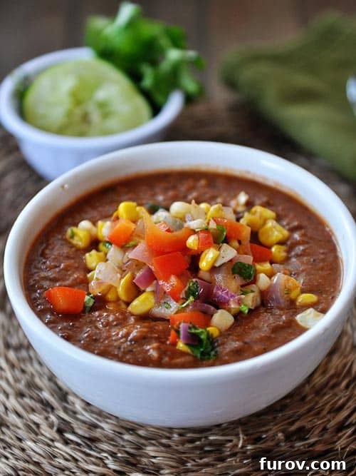 Hearty Smoky Tomato and Black Bean Soup with Zesty Corn Salsa 2 A vibrant bowl of Fire-Roasted Tomato and Black Bean Soup generously topped with fresh corn salsa, ready to be enjoyed.
