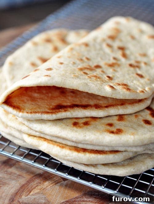A stack of freshly baked homemade flatbread cooling on a wire rack, ready to be enjoyed or stored.