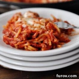 Close-up photo of Skillet Baked Spaghetti, showing the rich sauce, tender pasta, and melted, bubbly cheese on top.
