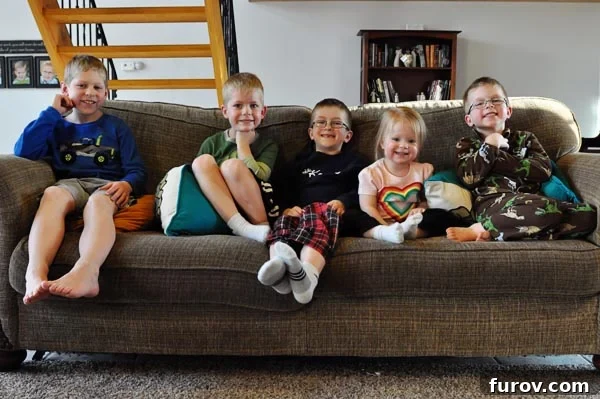 five happy children sitting closely together on a cozy couch, enjoying a family movie night