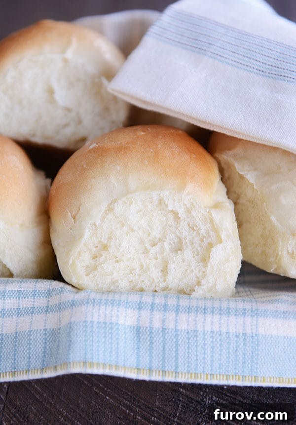 French bread rolls on a white and blue napkin inside a basket. 