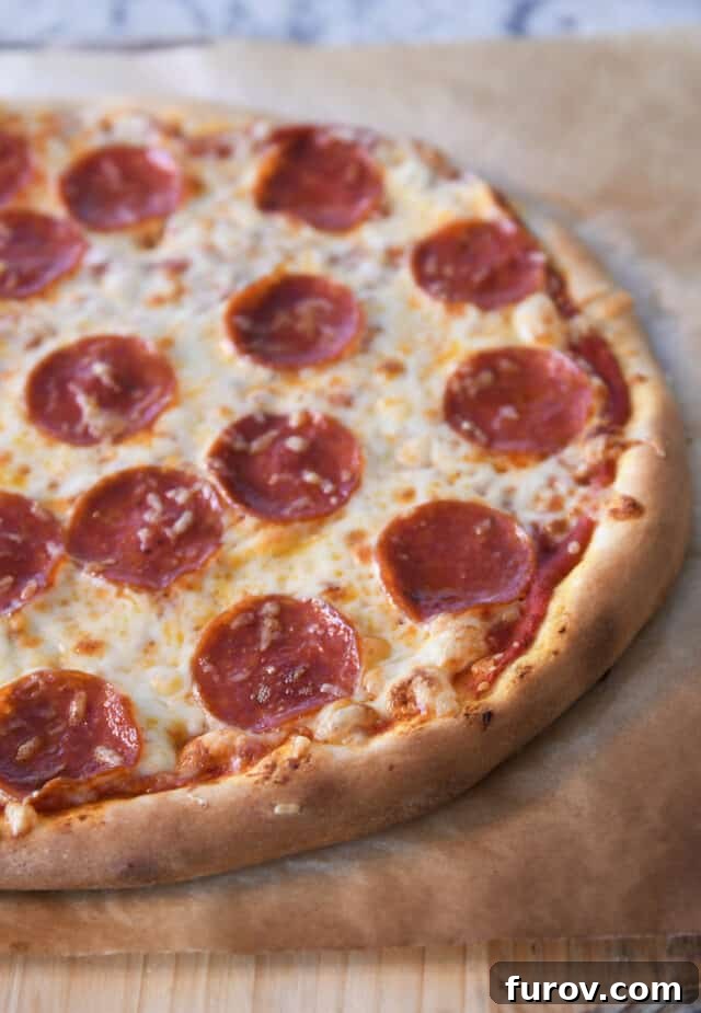 Fast and Flawless Pizza Dough 2 Golden, crispy pepperoni pizza crust on parchment paper, fresh from the oven.