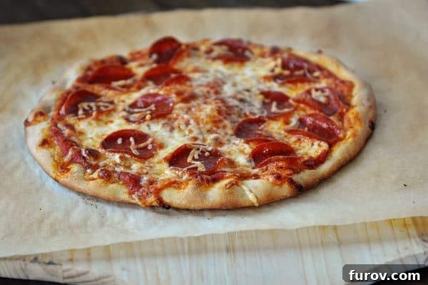 Fast and Flawless Pizza Dough 11 Homemade, baked pepperoni pizza on a piece of parchment paper, showcasing a golden crust.