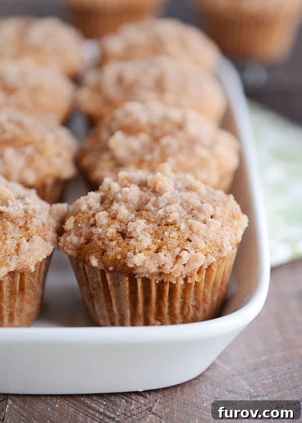 A white dish filled with perfectly baked pumpkin muffins, each with a streusel topping.
