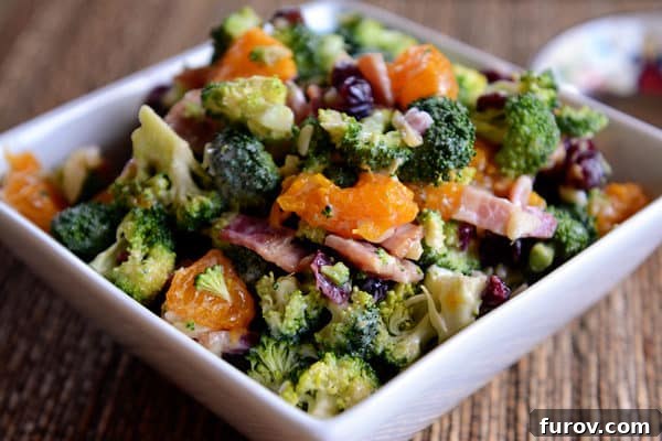 Zesty Mandarin Broccoli Salad 2 A bowl full of a mandarin, broccoli, bacon, and craisin salad.