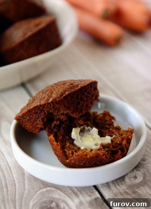 A golden brown muffin split in half with a pat of butter on the inside sitting in a small white ramekin, showcasing its soft interior.