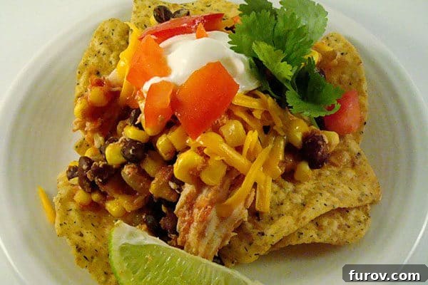 Vibrant Slow Cooker Southwest Chicken Stacks served over a bed of crispy tortilla chips, garnished with fresh cilantro and lime wedges.