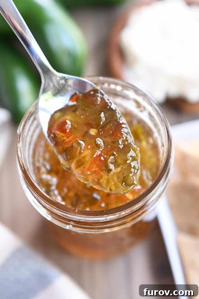 Spoon with vibrant green and red jalapeno hot pepper jelly, ready to be served.