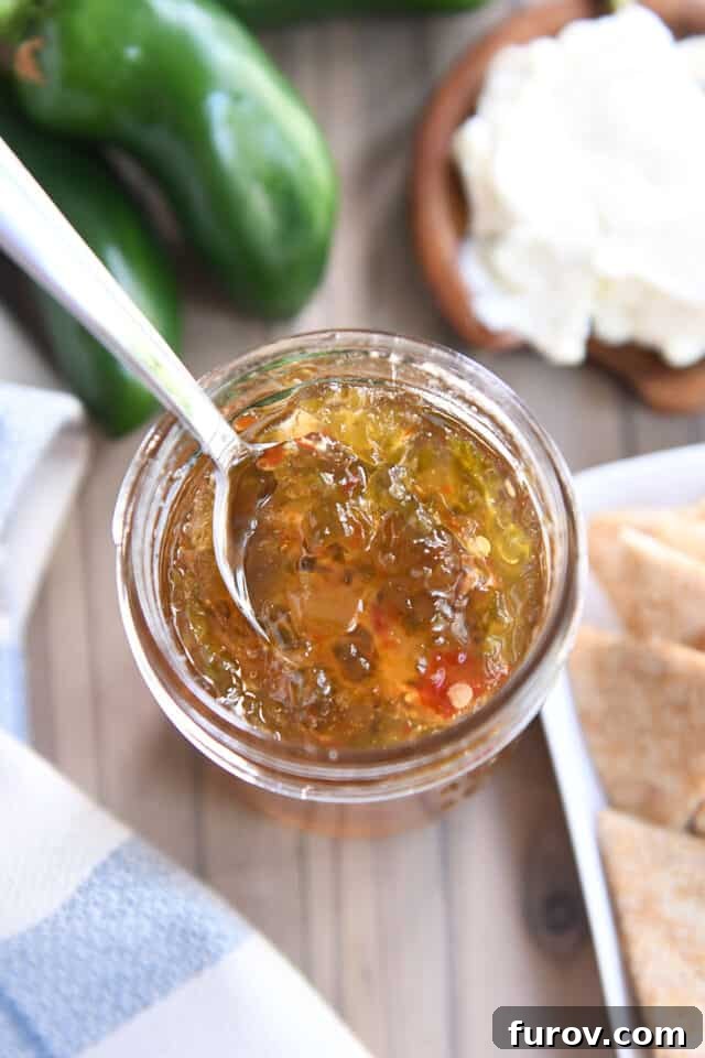A close-up shot of a spoon holding a glistening dollop of homemade jalapeño jelly.