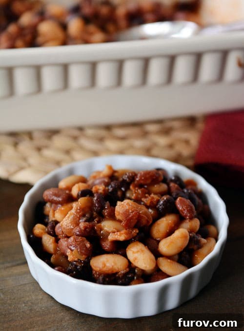 Mom's Legendary Calico Baked Beans 2 A small white ramekin filled with bacon-filled baked beans, garnished with fresh parsley.