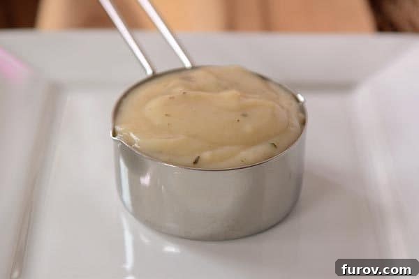 Ev Yapımı Konsantre Kremalı Tavuk Çorbası ve Tariflerde Kullanımı 3 A metal measuring cup full of cream of chicken soup.