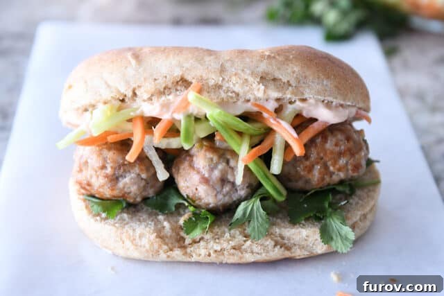 A freshly assembled Banh Mi meatball sub on parchment paper, ready to be enjoyed.