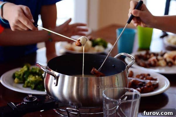 Two individuals dipping various foods, including meat and vegetables, into a communal pot of melted cheese fondue.