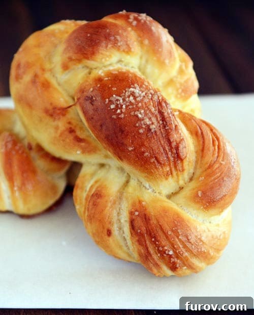 A perfectly golden brown baked pretzel twist, glistening with melted butter and sprinkled with coarse salt, ready to be enjoyed.