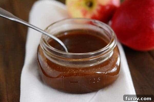 A small mason jar filled with delicious caramel sauce, a spoon resting inside, ready for a taste.