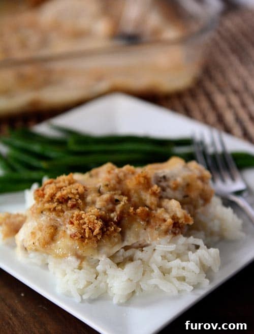 Golden Swiss Gratin Chicken 2 White rice topped with a crunchy-topped swiss cheese chicken breast, ready to be enjoyed.