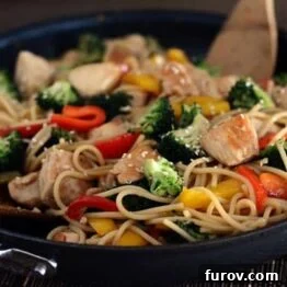 A close-up of the stir-fried chicken and vegetable lo mein in a cast iron skillet.