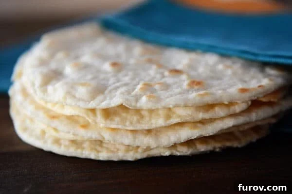 A stack of homemade cooked tortillas under a blue napkin.